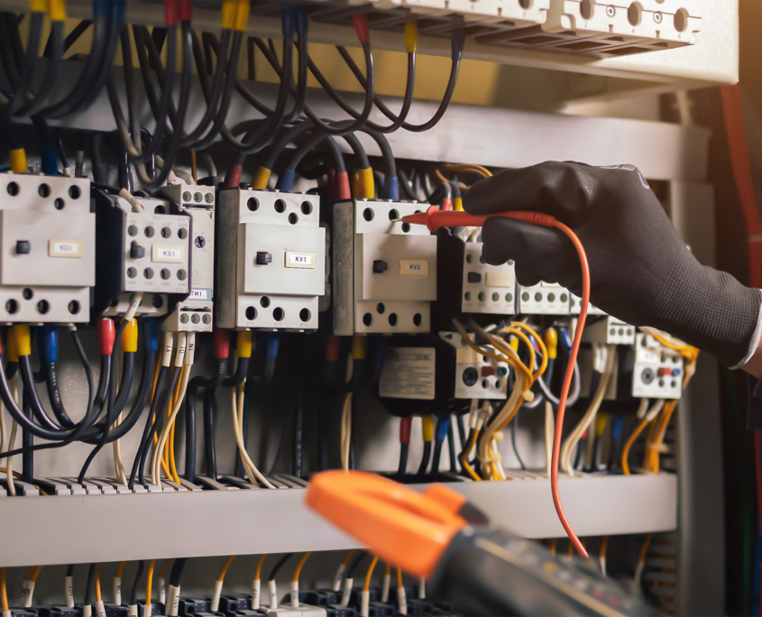 Side view of electrician working in electric panel with gloves on